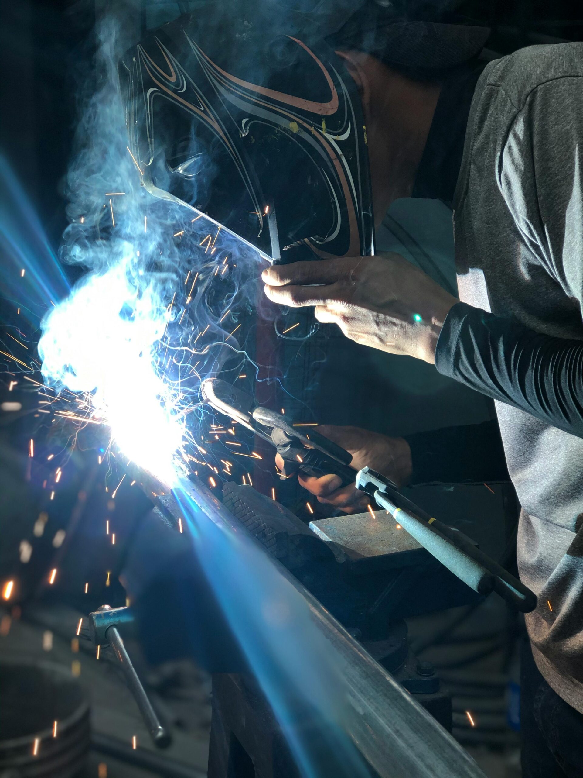 A close-up shot of a welder at work, surrounded by sparks and light.